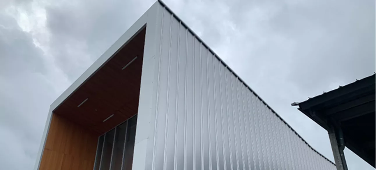 Angle d’un bâtiment moderne avec bardage métallique et sous-face bois de l’Aérogare de Deauville, réalisation de couverture par l’entreprise ENC en Normandie.