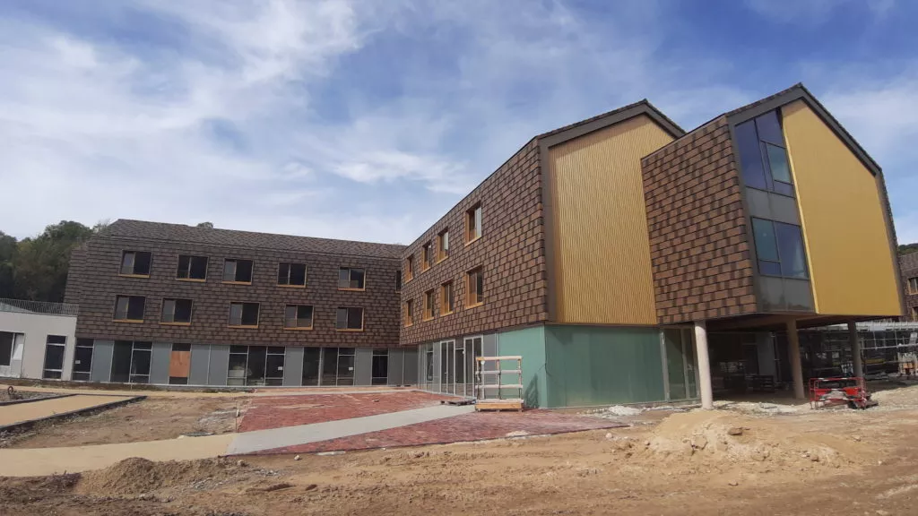 Chantier de bâtiment en construction avec bardage et zones de terrassement, entreprise de couverture en Normandie ISOTOIT